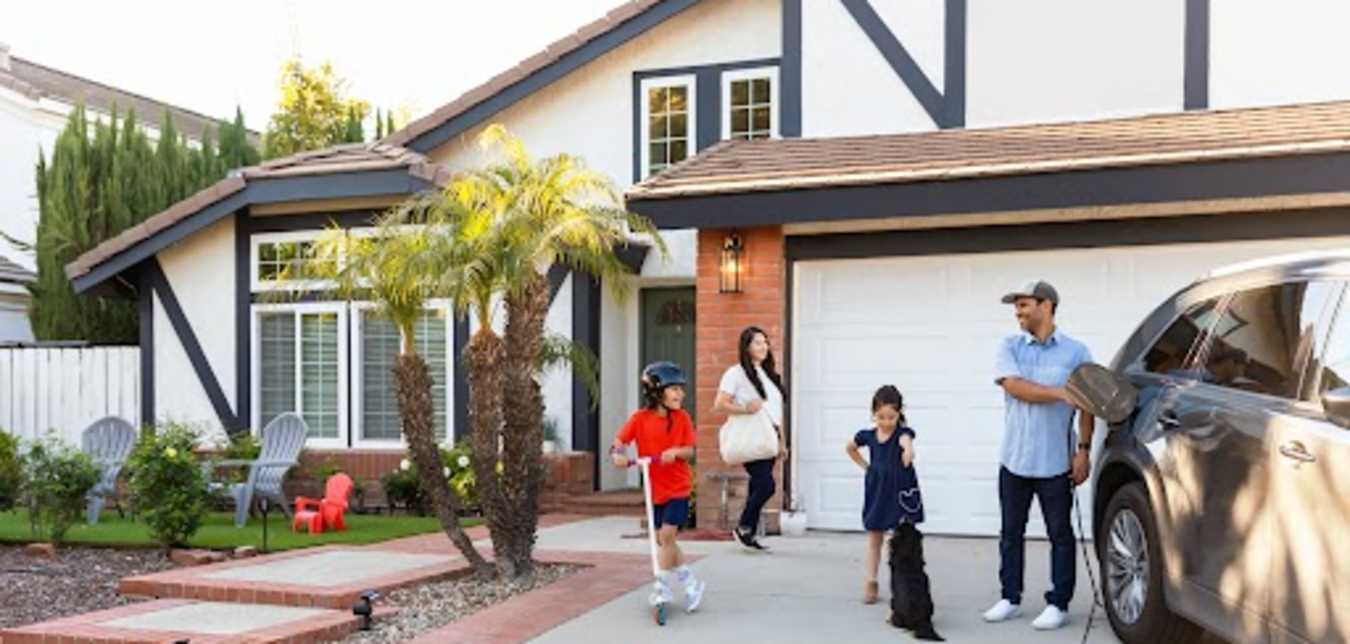 Family in the driveway of their home protected by AAA Insurance.