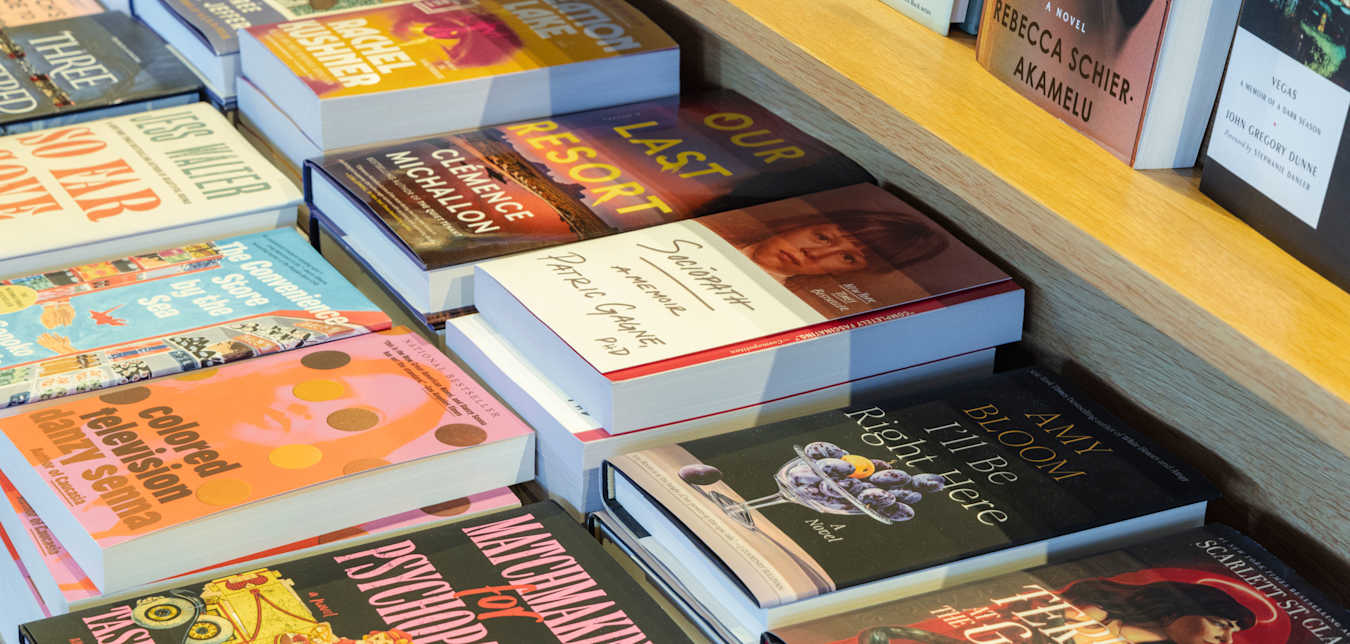 Stacks of hardcover books displayed on a table at an independent bookstore. 