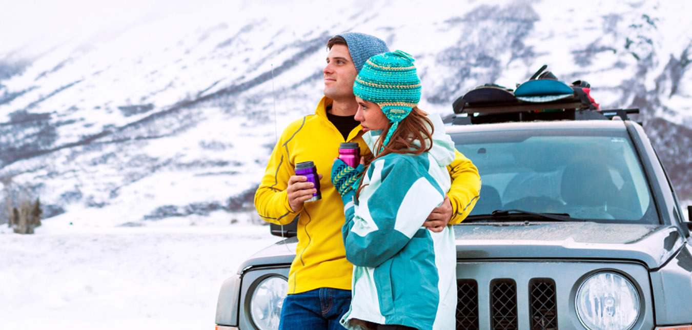 couple standing in front of jeep by a snowy mountain