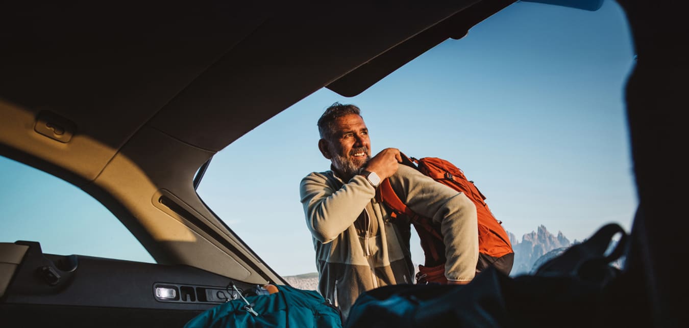 man grabbing backpack from trunk of car