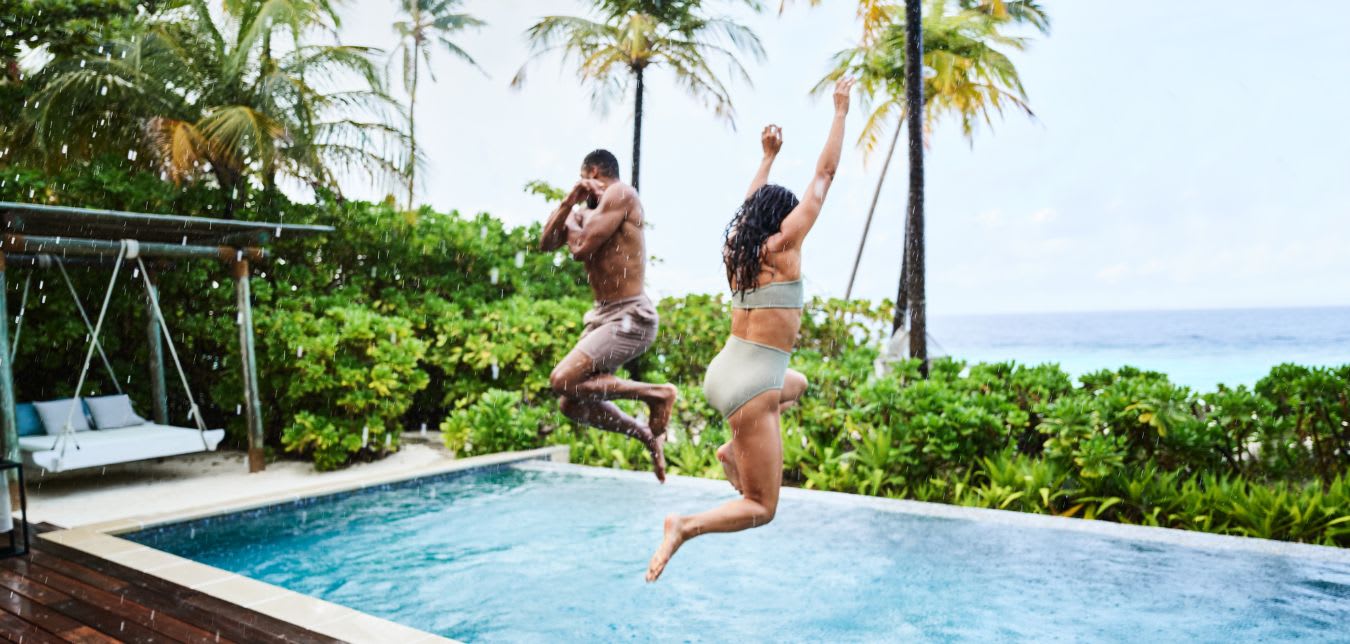 couple jumping into a pool at a Hilton hotel