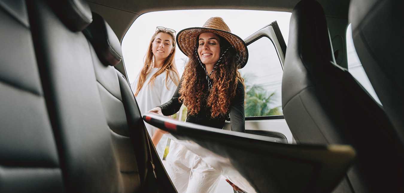 Women unloading a surfboard from their Hertz car rental