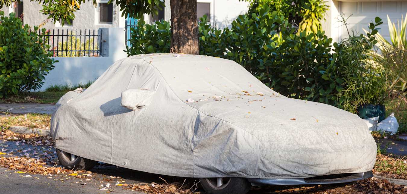 A car under a cover parked on a street.