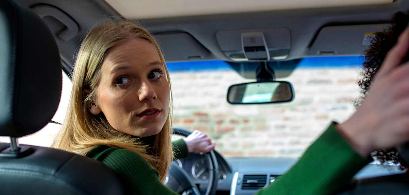 A driver looks over her shoulder as she backs up her car.