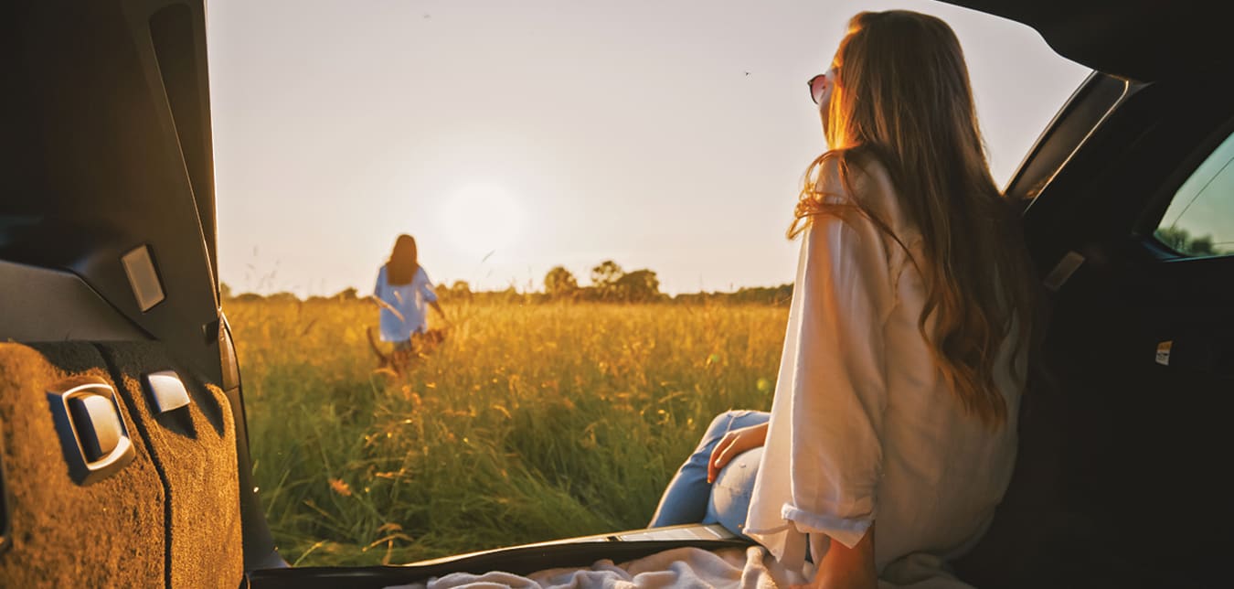 woman sitting in the trunk of the car in a field