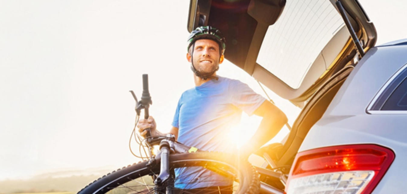 AAA Member unloading a mountain bike from his car at sunset
