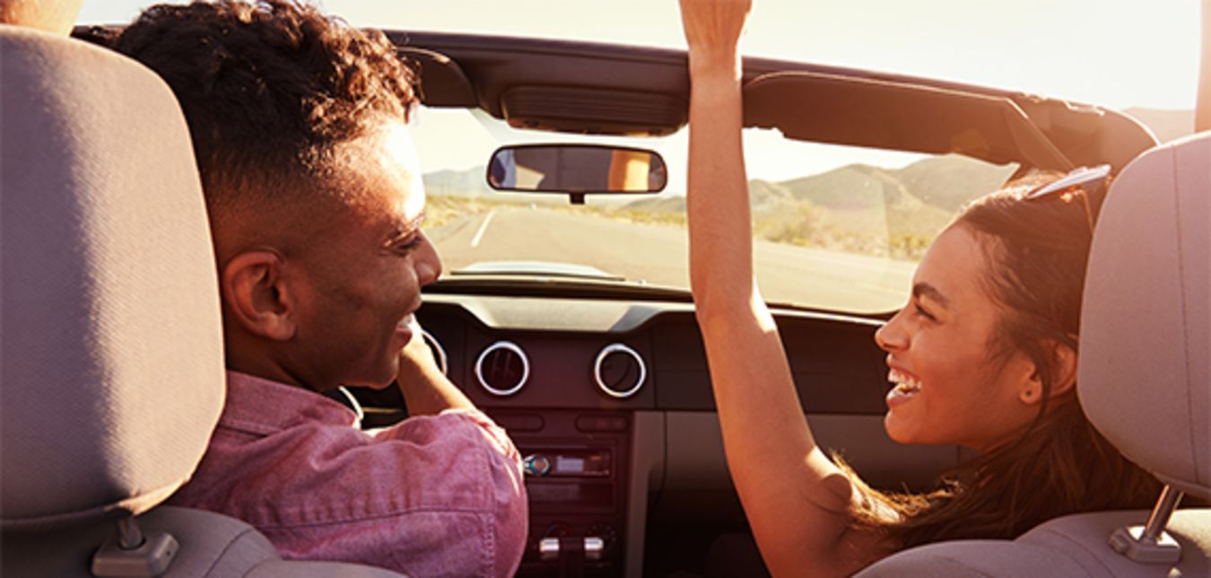 a couple taking a road trip in a convertible who saved money bundling AAA Home and Auto Insurance