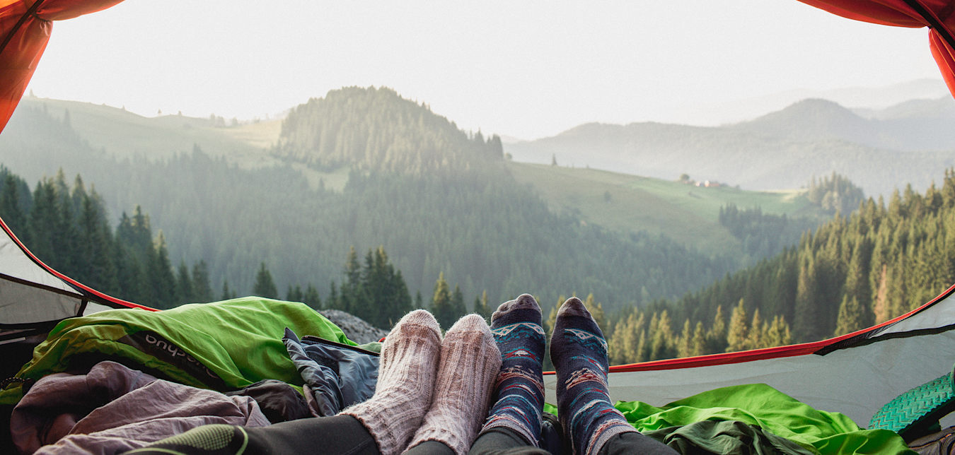 Mountain views through the flap of a tent.