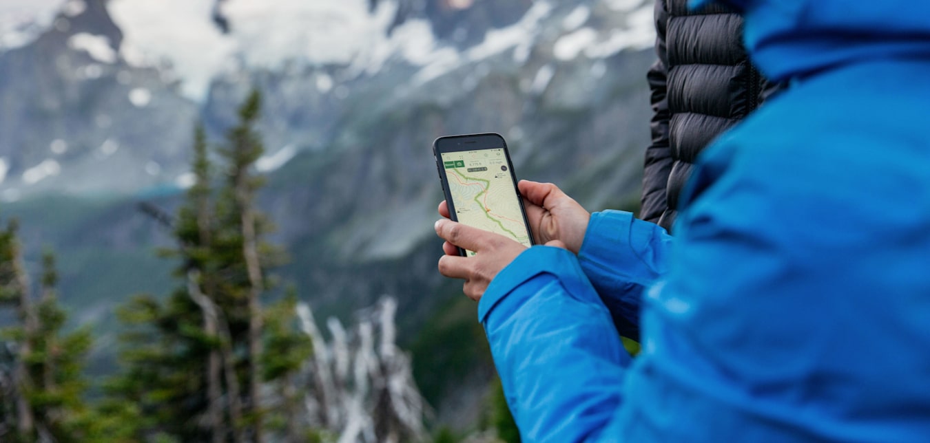 A woman uses Gaia GPS when hiking in the spring.