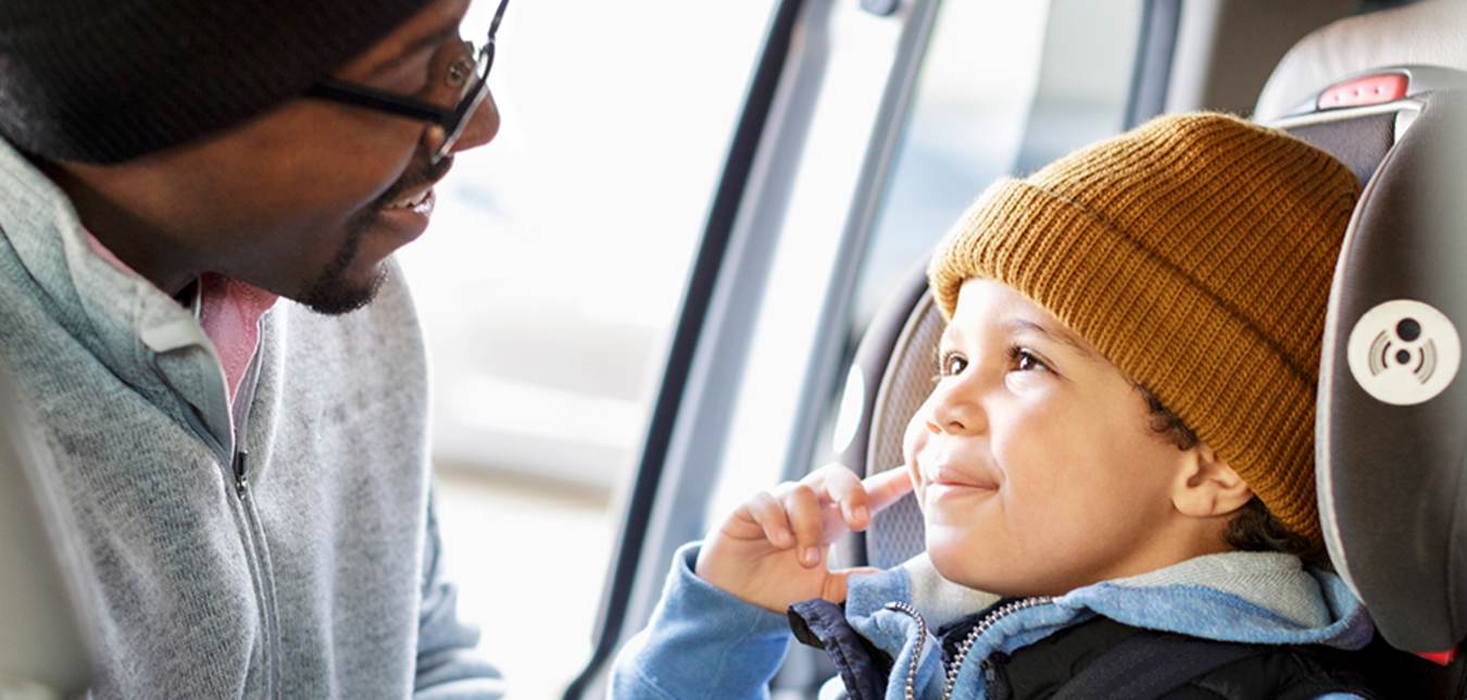 father buckling child in safety seat in hertz car
