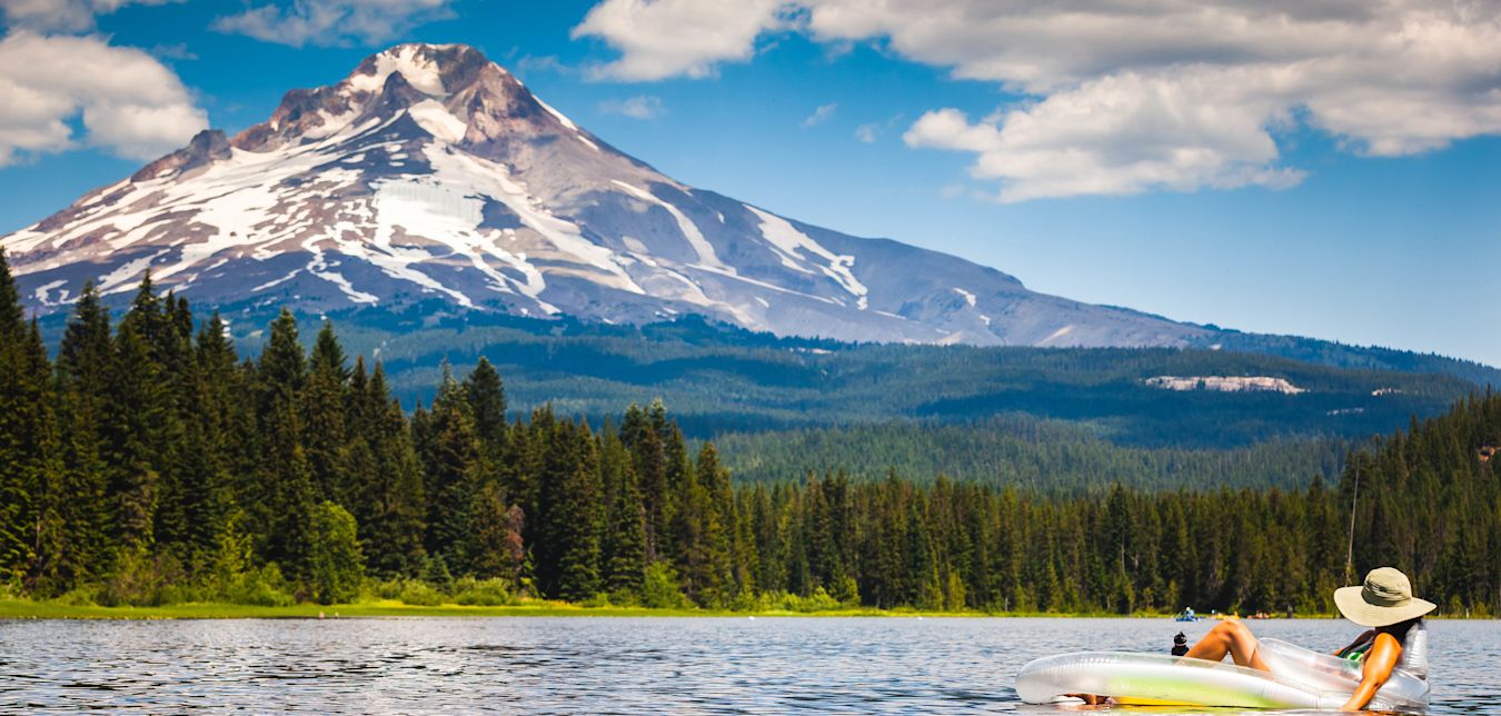 A woman floats on Lake Trillium in Oregon with Mount Hood in the background.