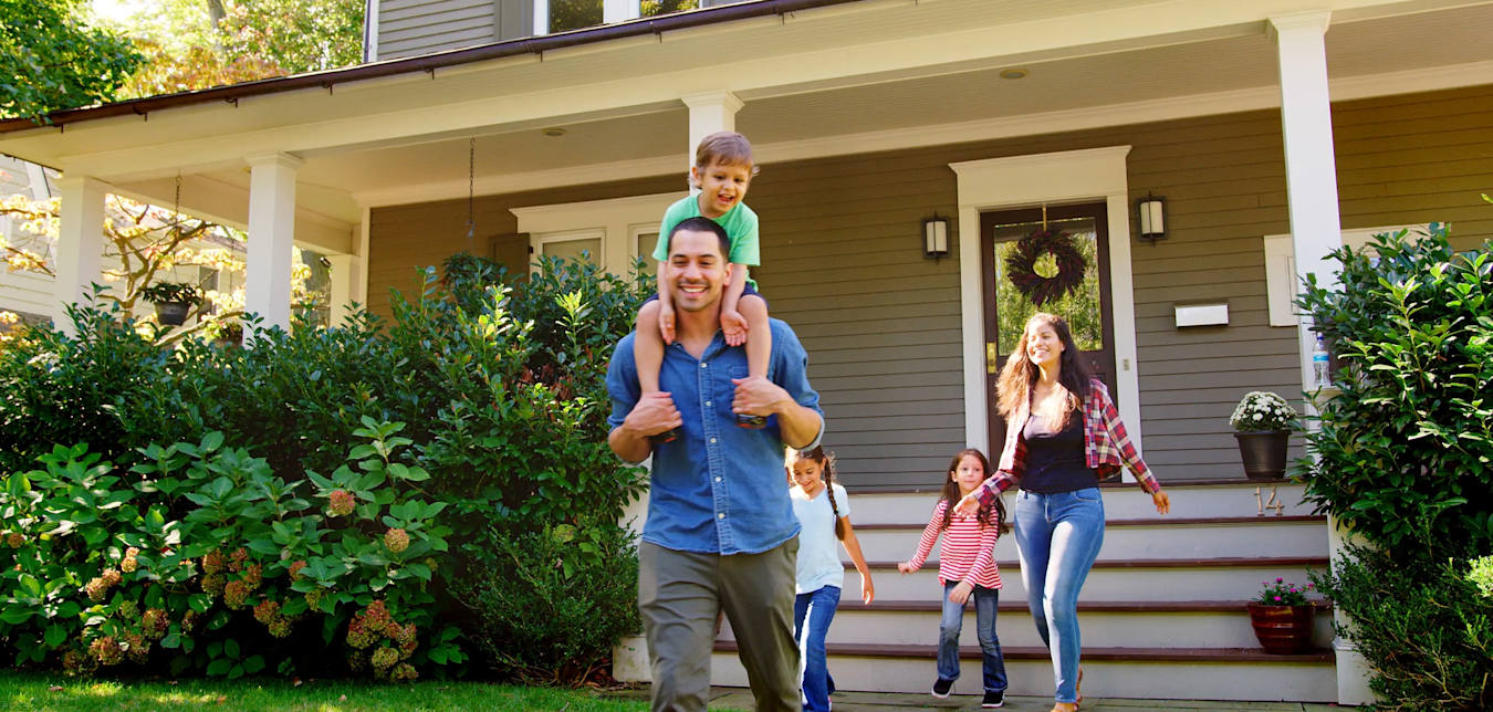 Family walks in the front yard of their home protected by AAA Insurance.