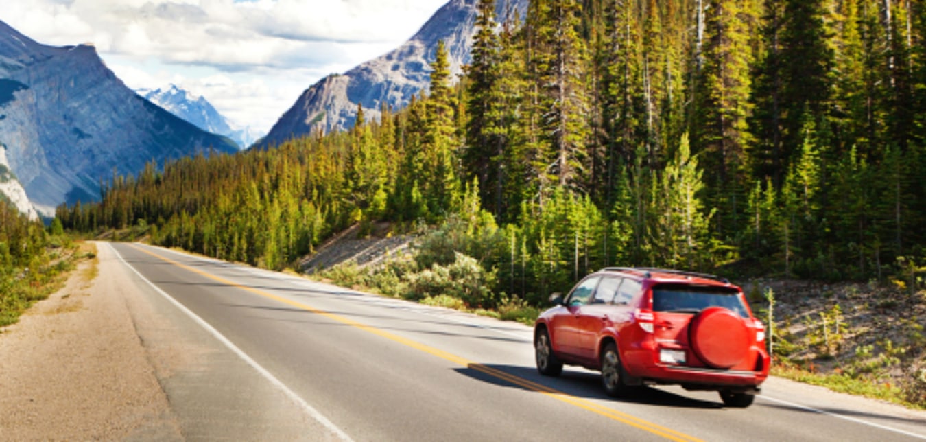 Car driving down street with mountains in the distance