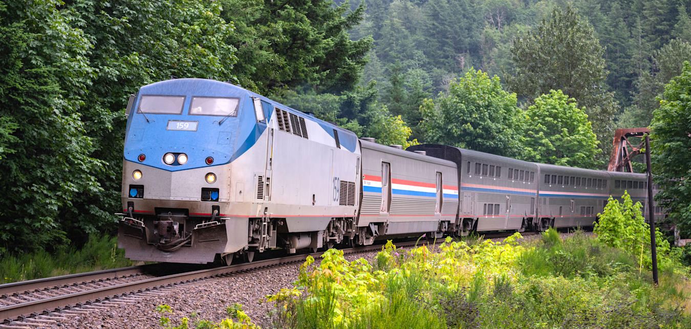 Amtrak's Empire Builder train on a forested railroad track.
