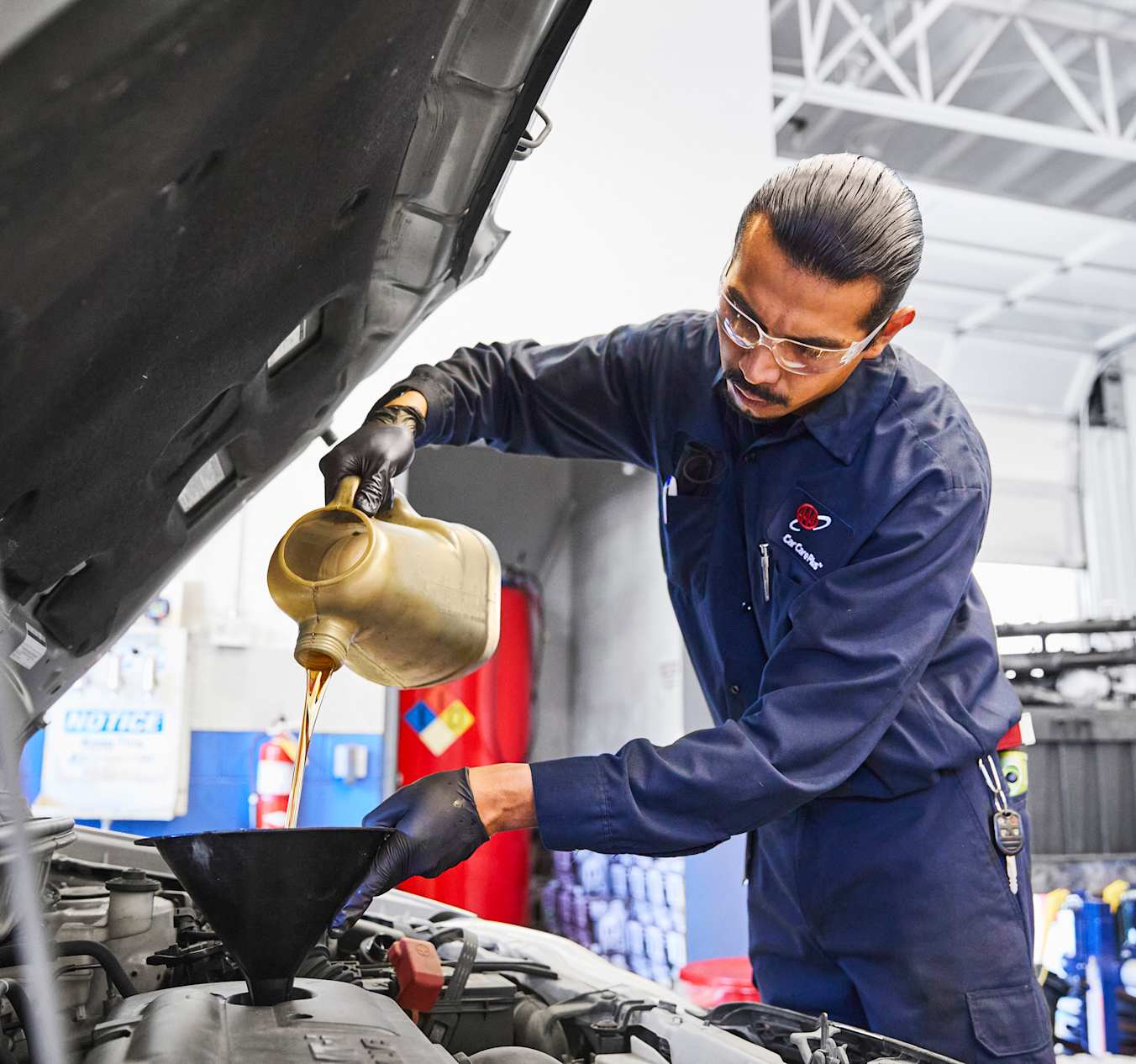 AAA mechanic working on a car with the hood open at an auto repair shop