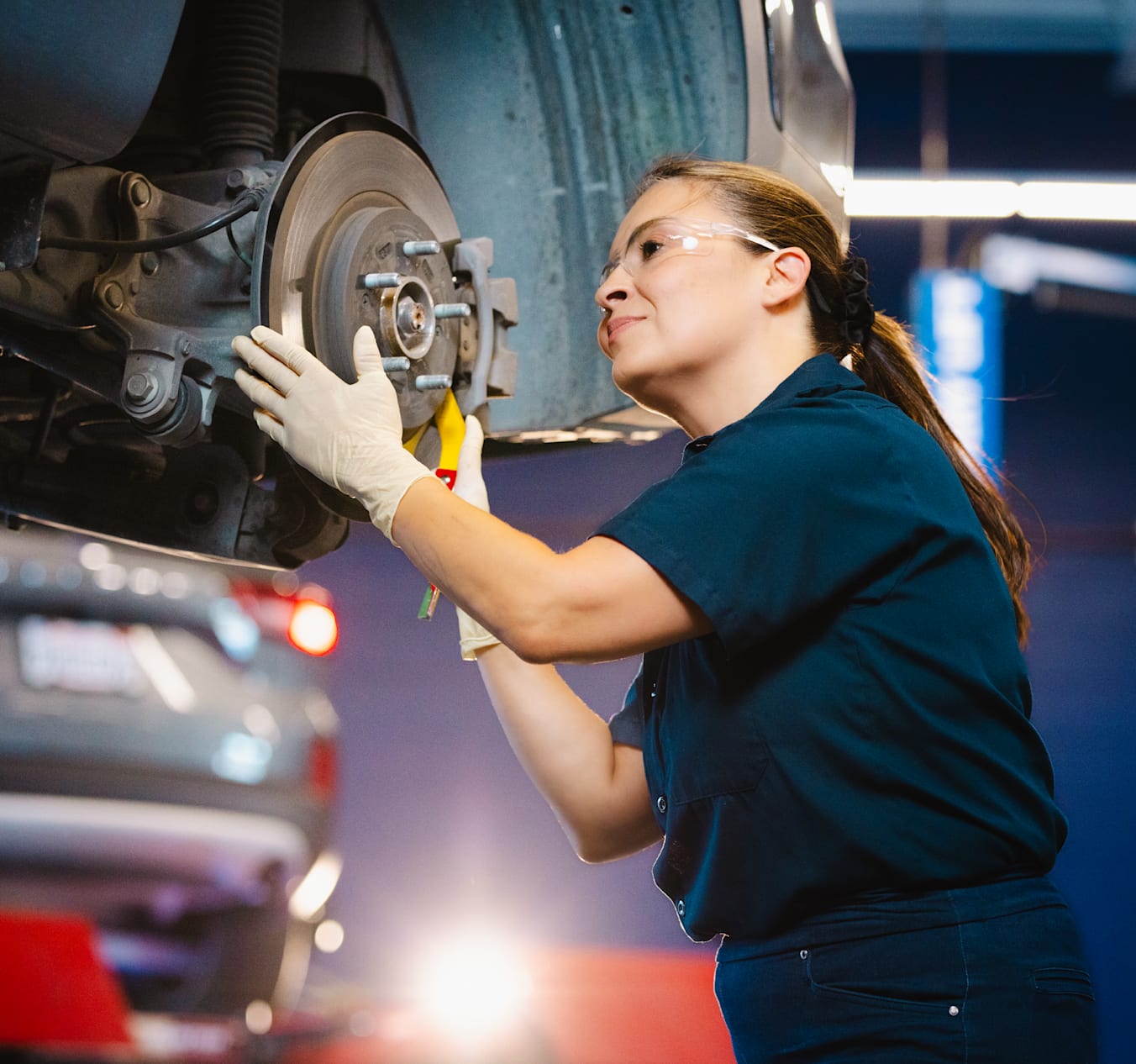 AAA mechanic working on a car with the hood open at an auto repair shop