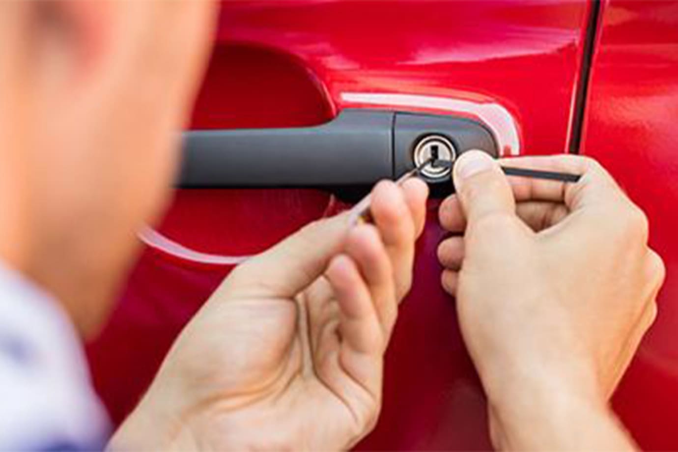a man uses a lock pick to get into a red car door