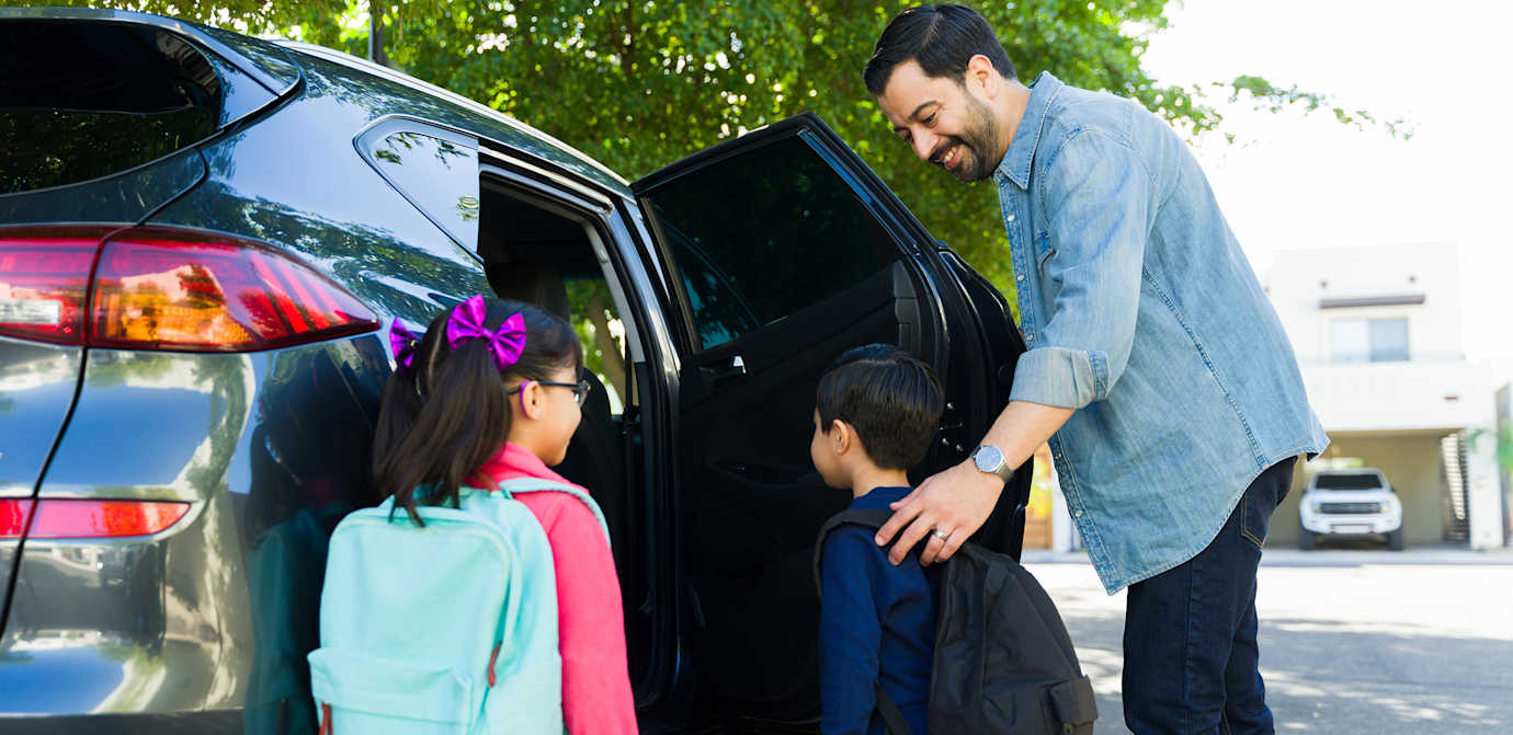 Husband helping kids into car