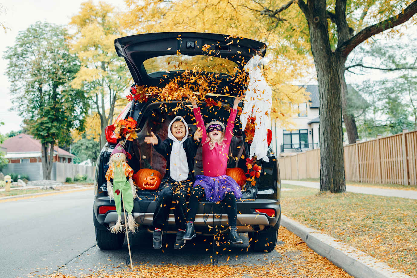 Kids sitting in trunk of car with Halloween costumes on