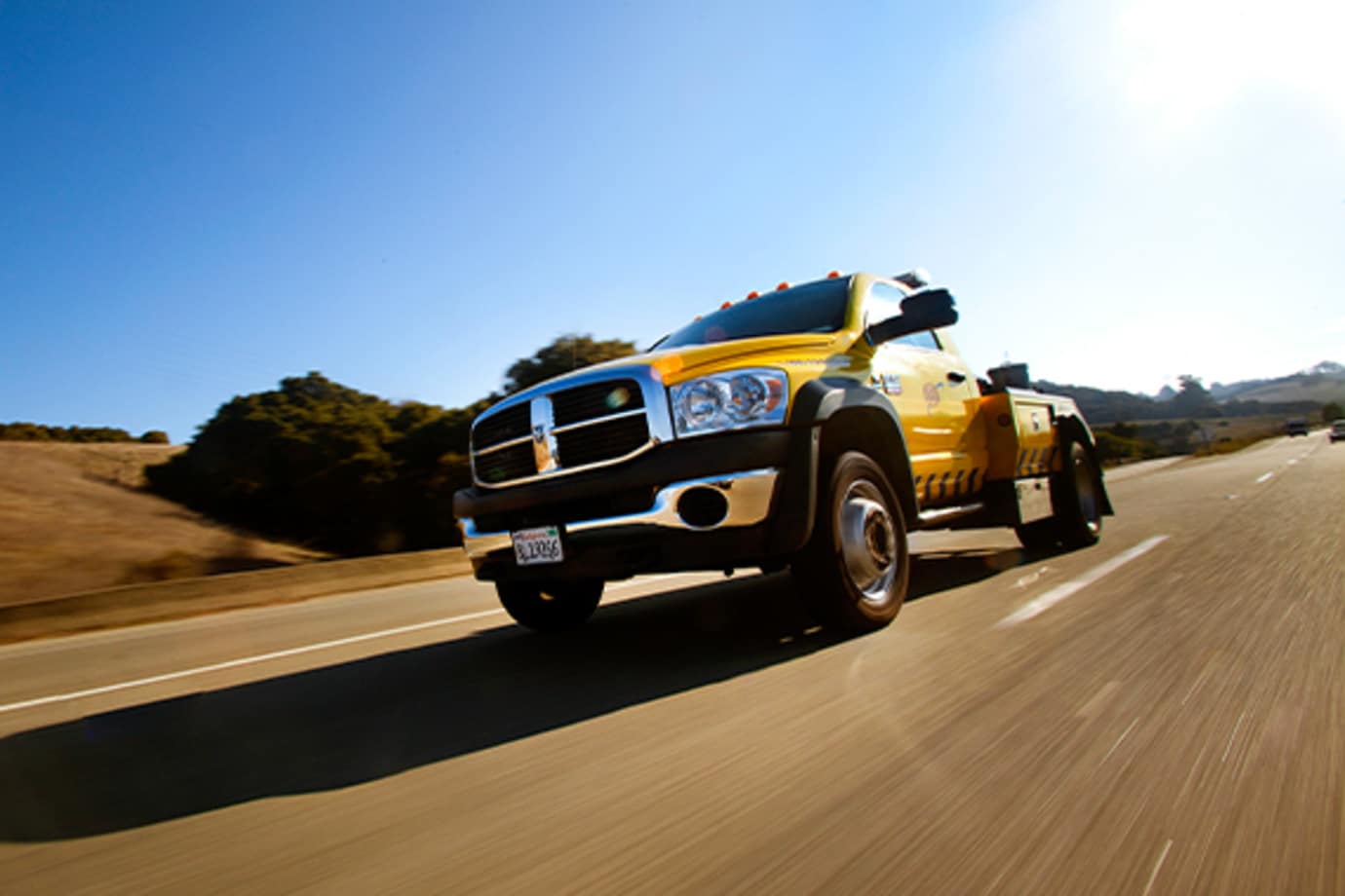 a tow truck driving down the highway on a sunny day