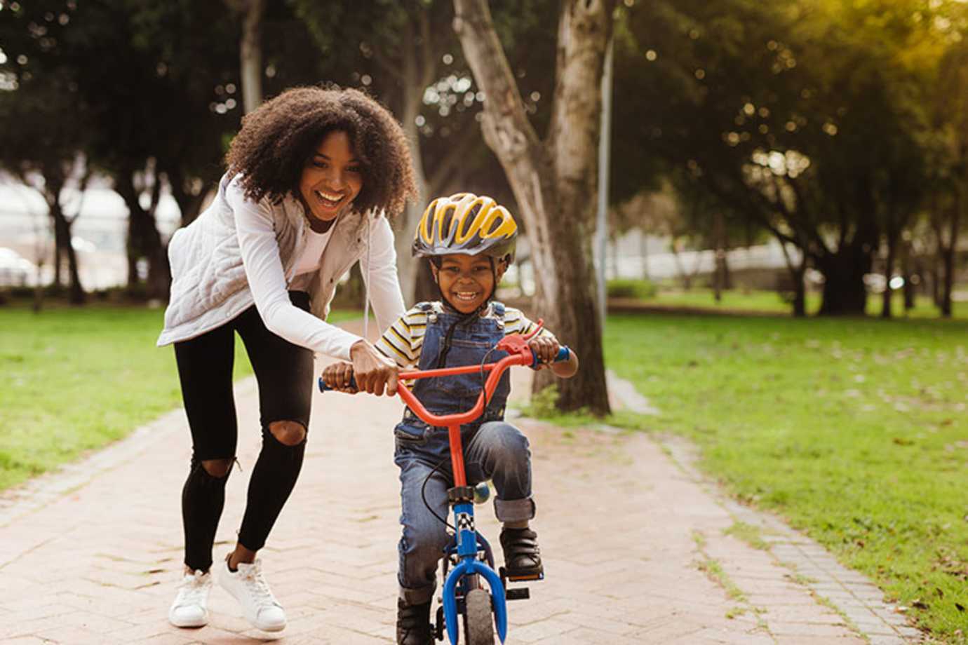 A AAA Life Insurance customer helps her son learn to ride his bike.