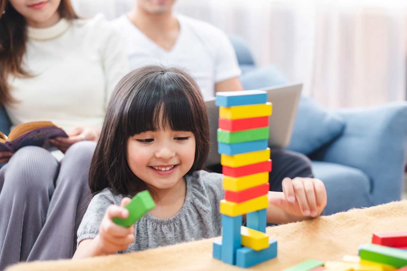 young girl playing with legos while her parents watch in a house protected by AAA home insurance