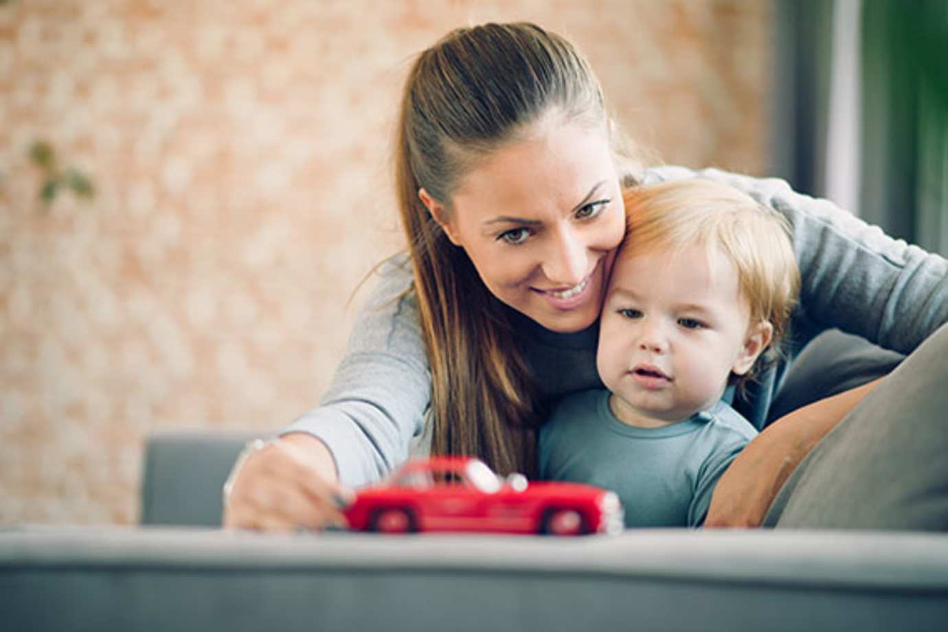 a mom with AAA life insurance plays on the couch with her toddler son