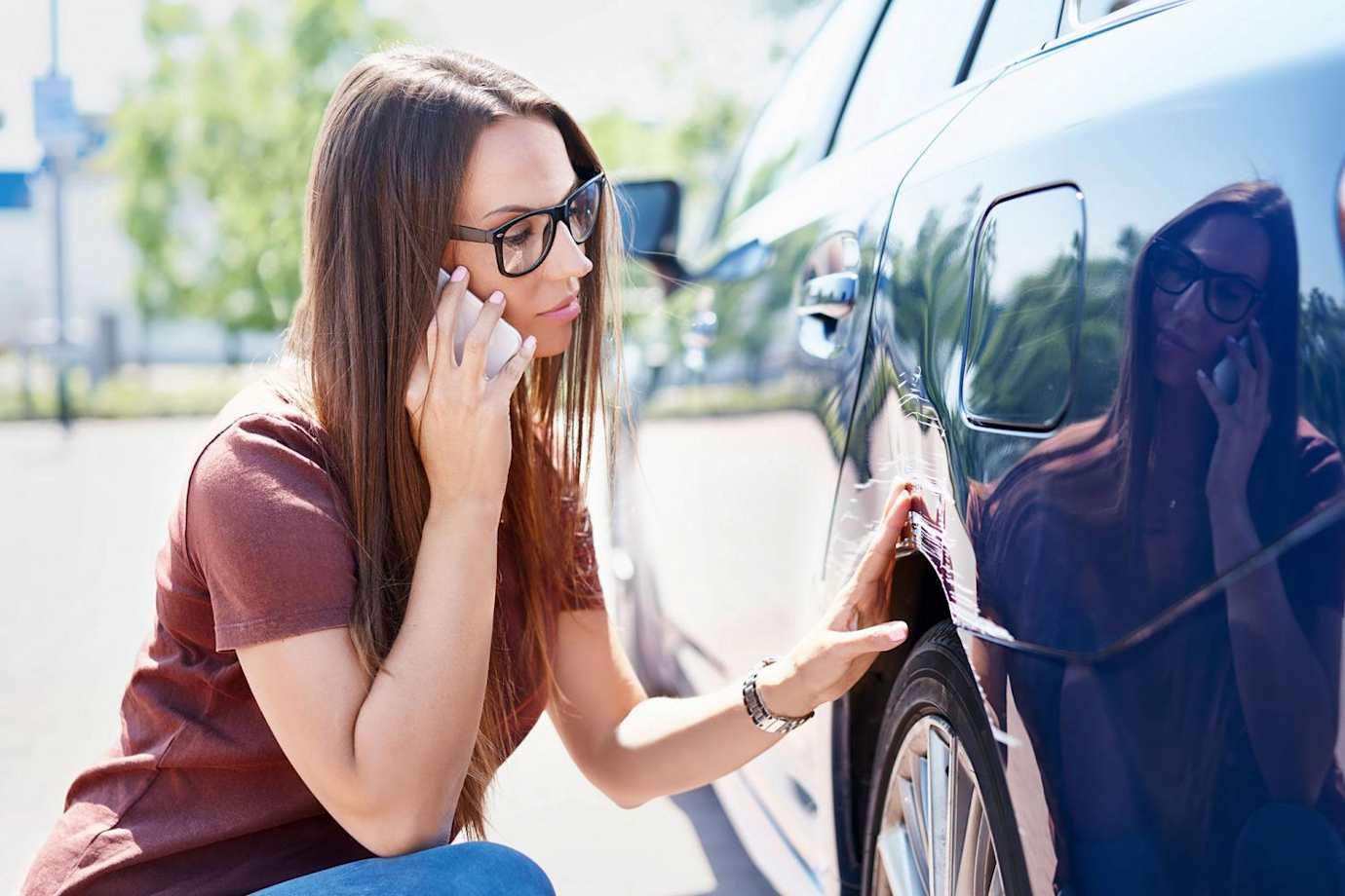 A woman calls her insurance agent after her car was damaged in a hit-and-run crash.