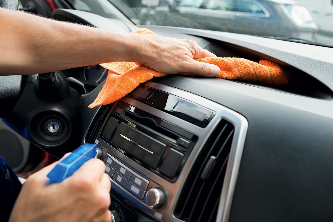 A driver cleans their car dashboard.