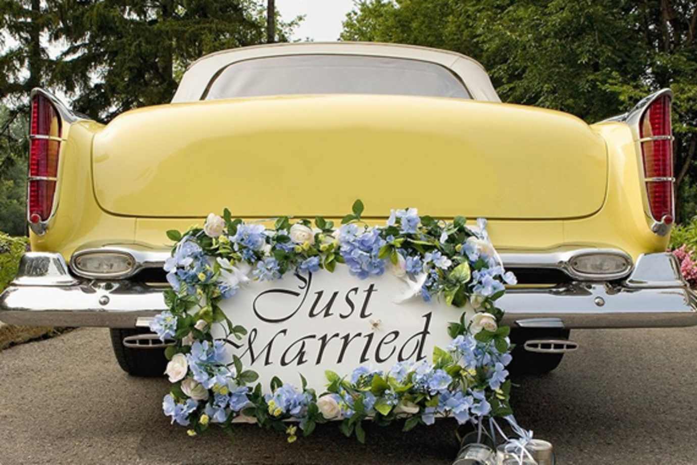 yellow antique car with a just married sign on the back bumper