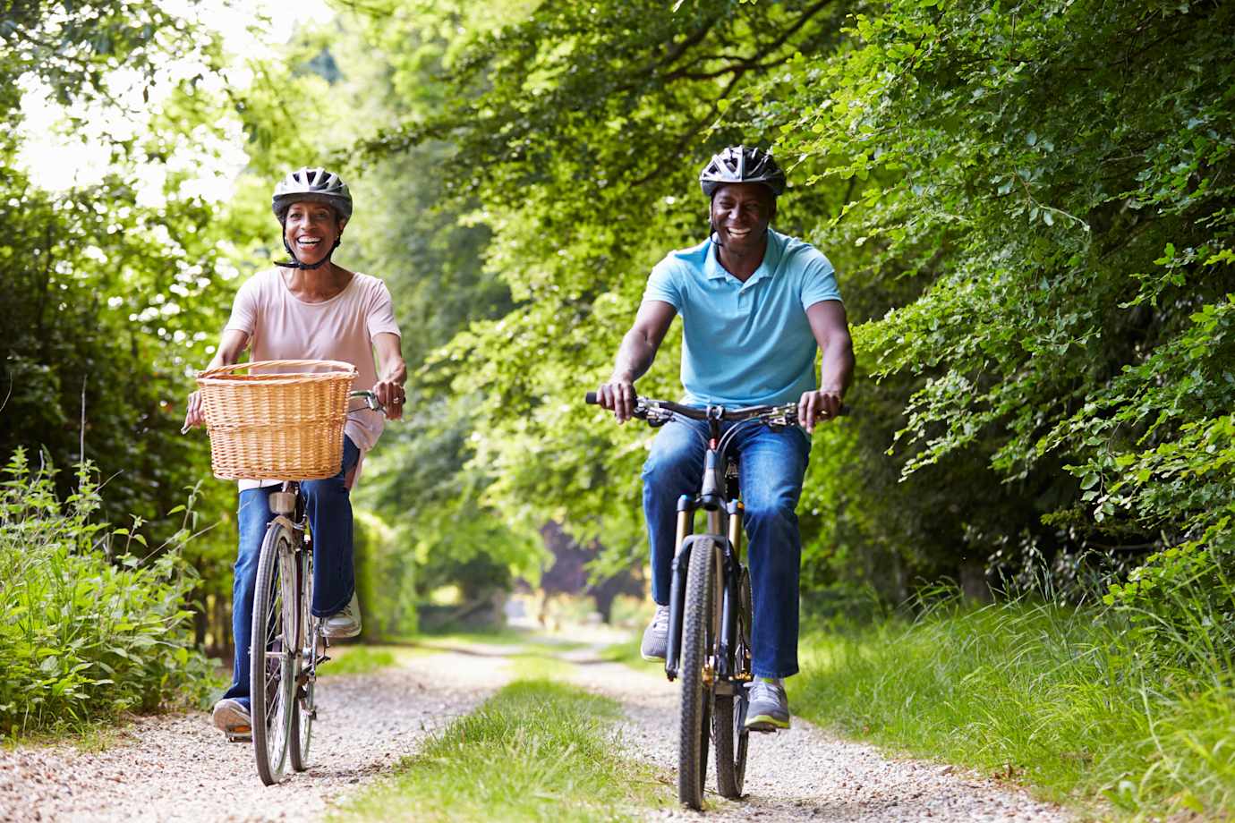 a couple covered by AAA Life ride their bikes on shaded path