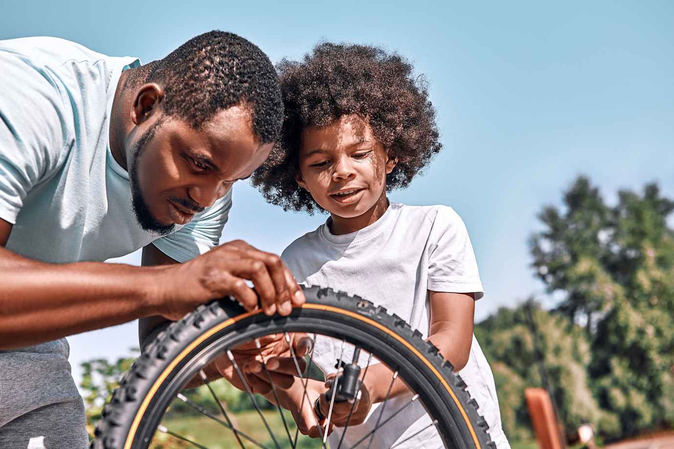 A dad and his son add air to the son's bike tire.