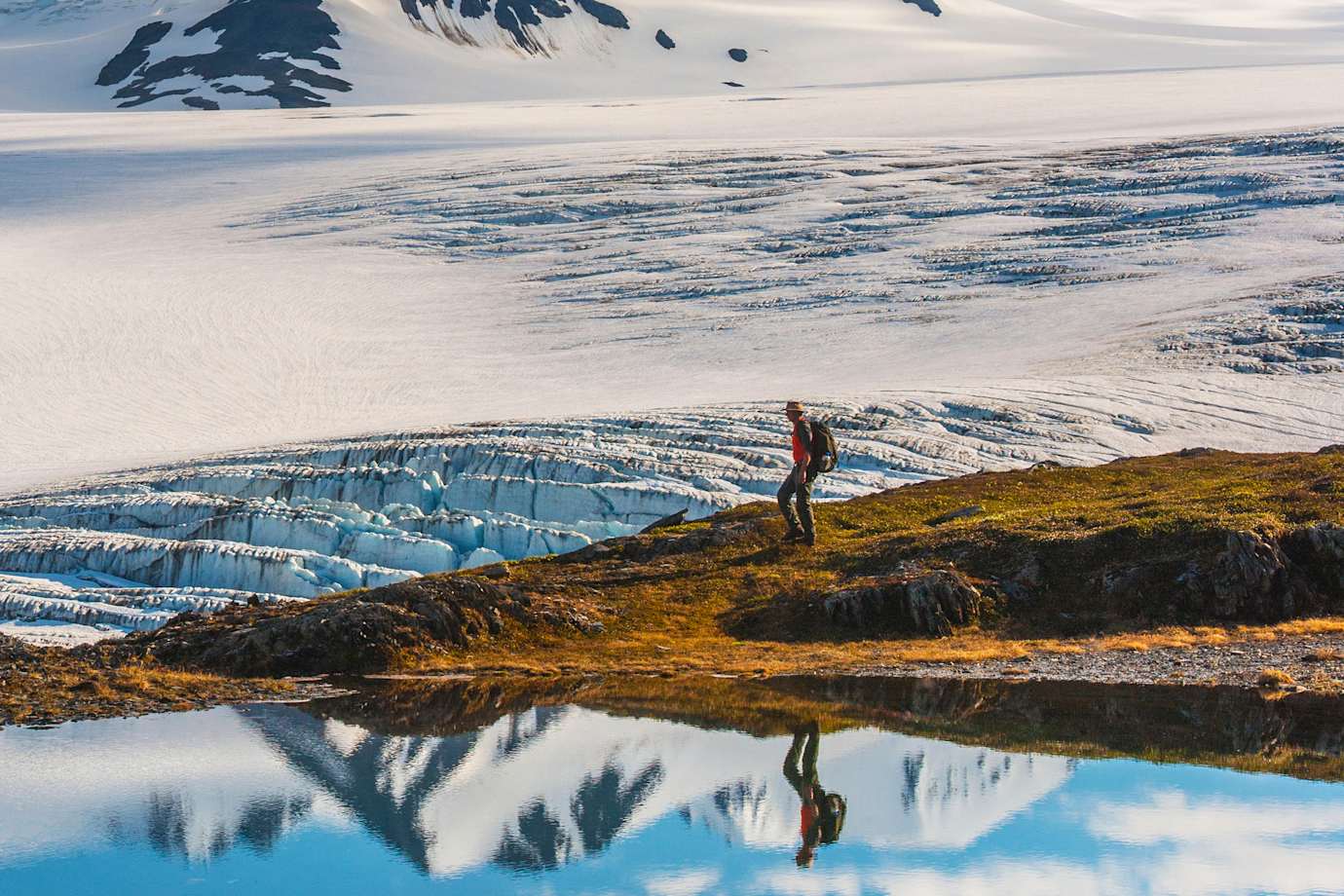 A man hikes past the Harding Icefield with the Nunatak peaks in the background in Kenai Fjords National Park.