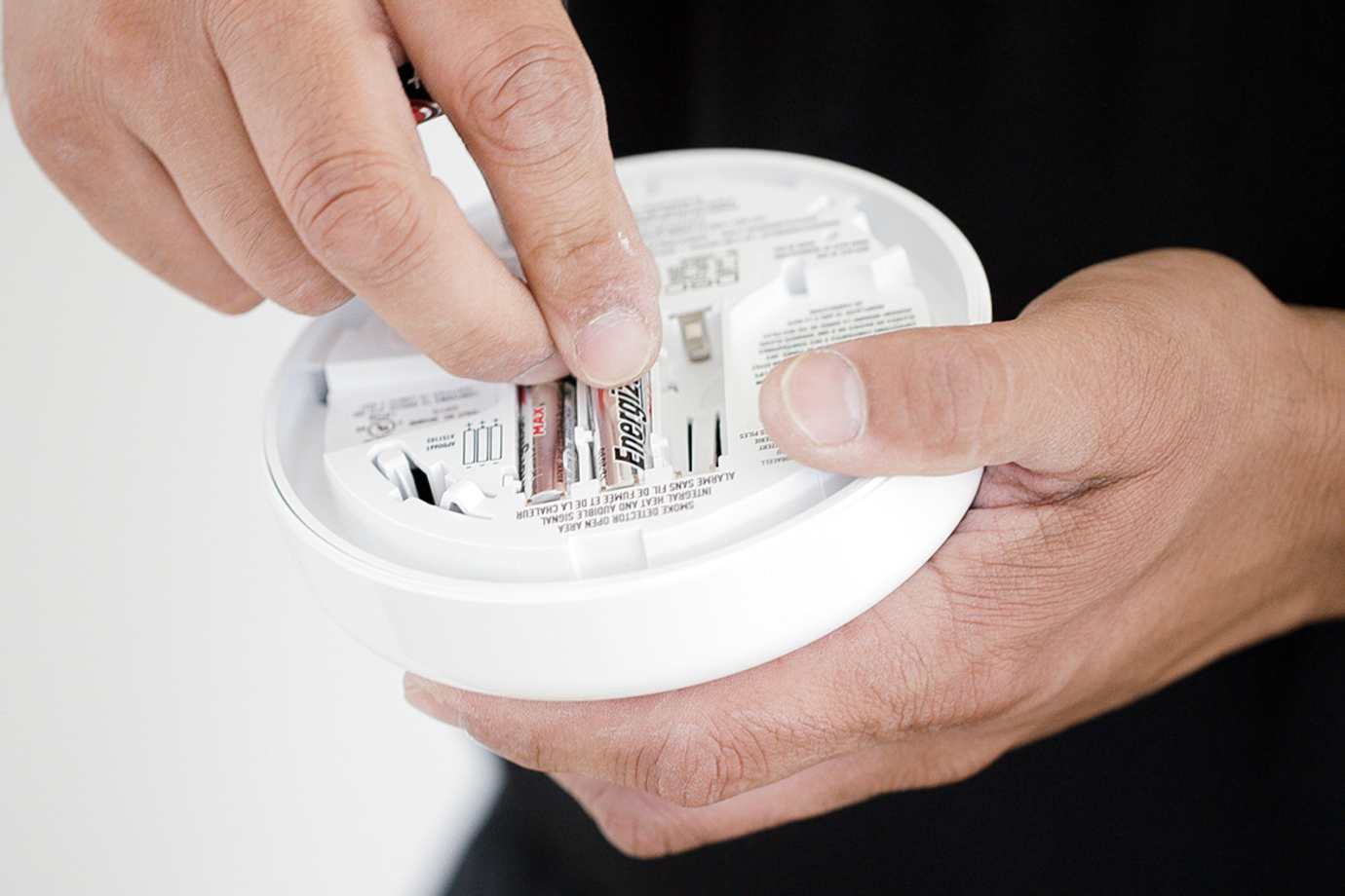 Person changing batteries in smoke alarm