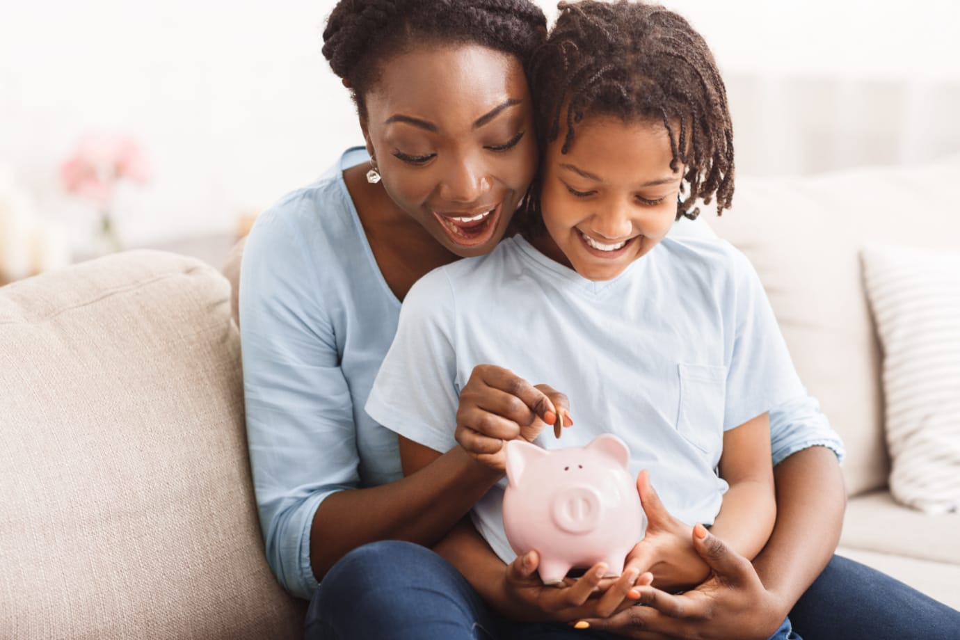 Mother and daughter putting money into a piggy bank