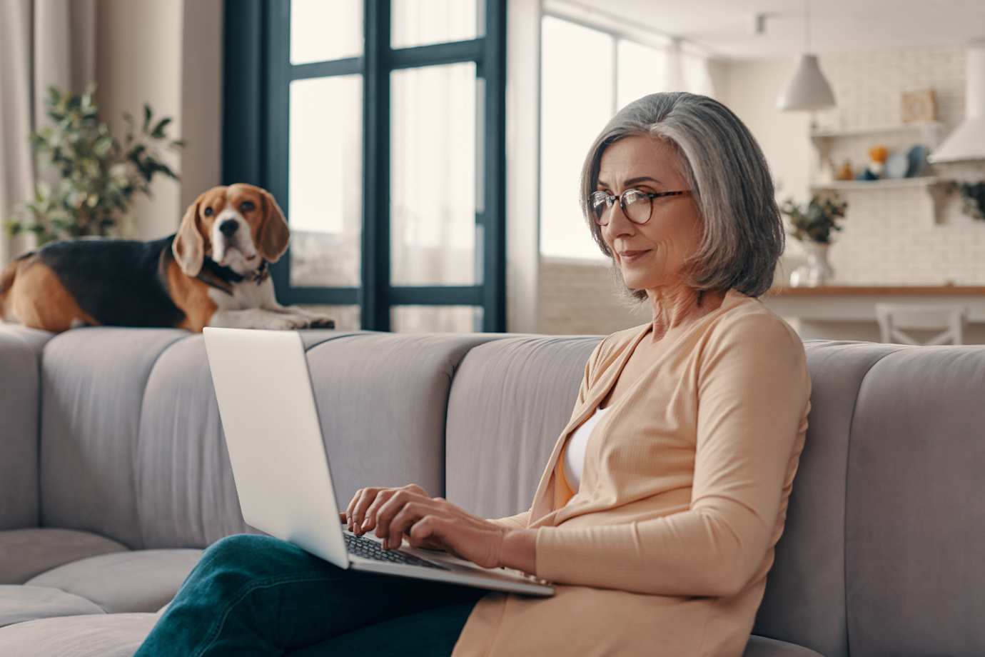 Woman sitting on couch while browsing on laptop