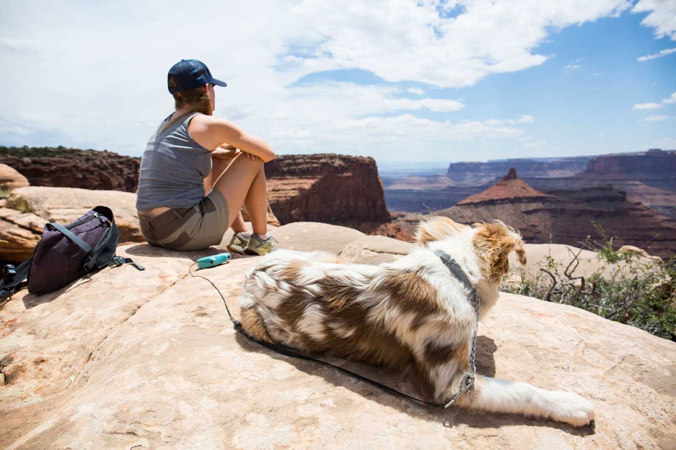 A hiker rests along a hike with her dog in Utah.
