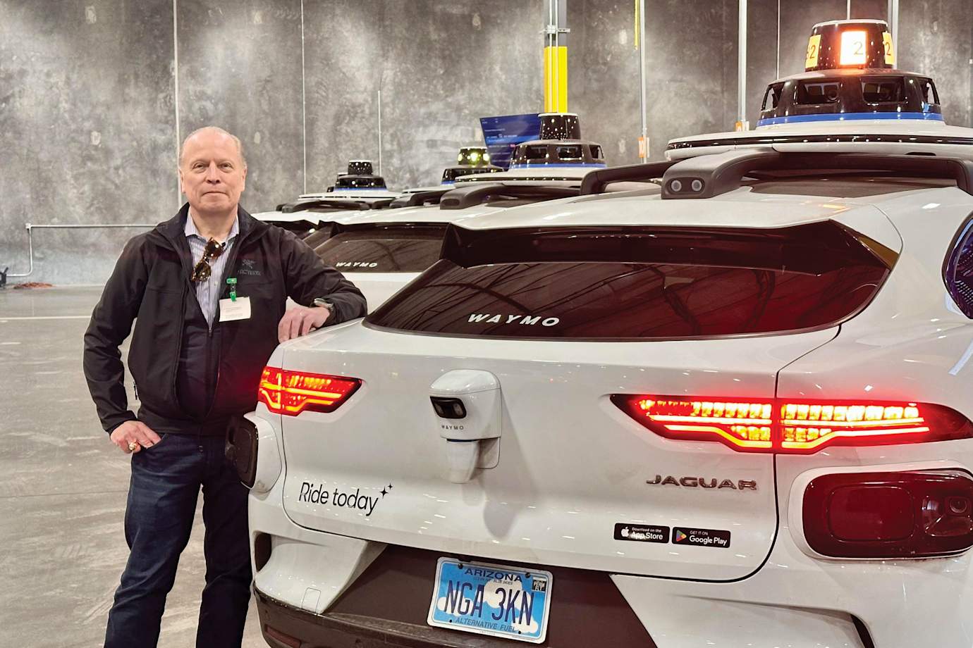 AAA Mountain West Group CEO Marshall stands next to a Waymo self-driving vehicle.