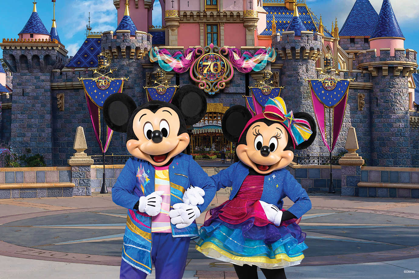 mickey and minnie in front of disneyland castle for 70th anniversary