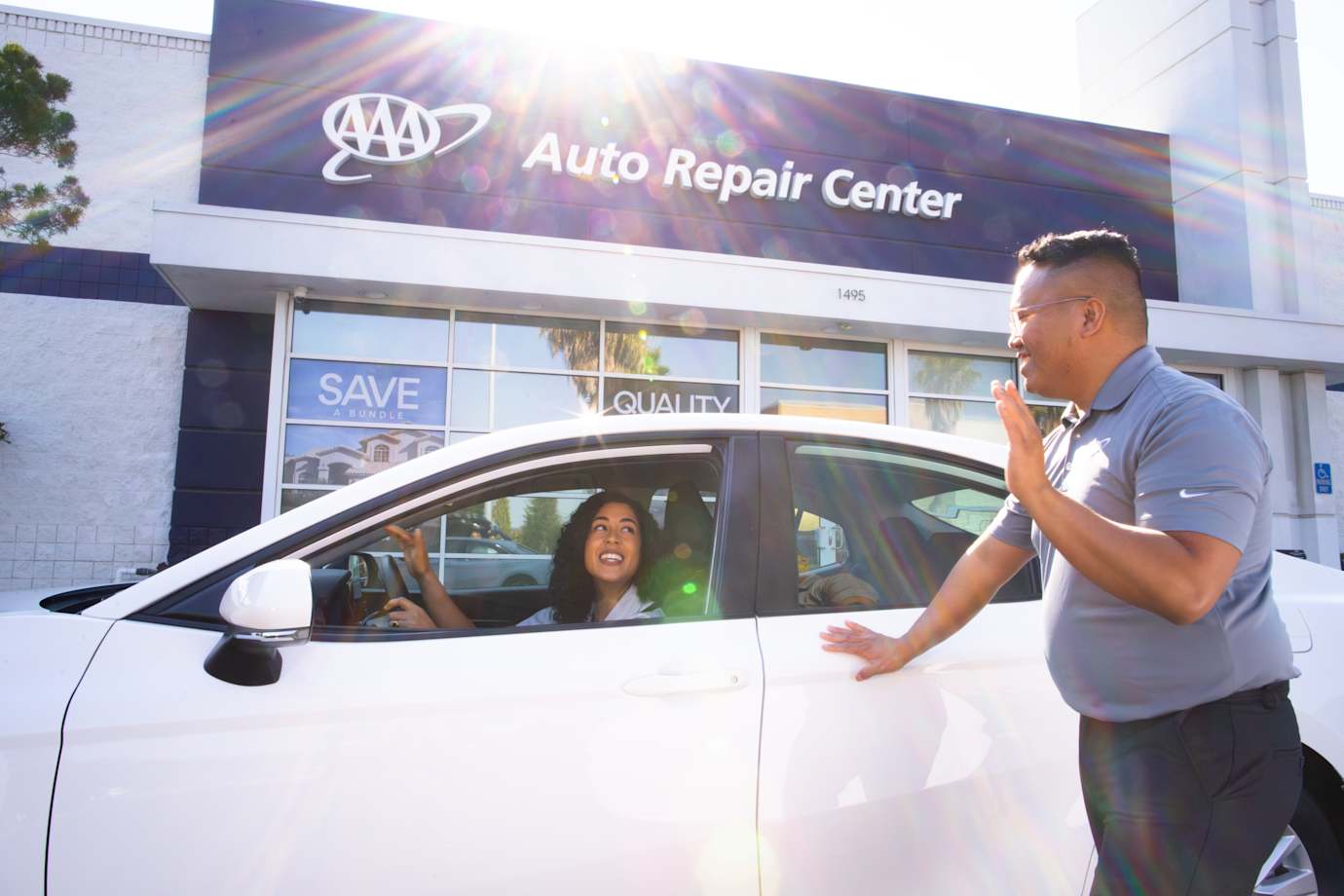 AAA auto repair center staff waves goodbye as a driver pulls away in their car