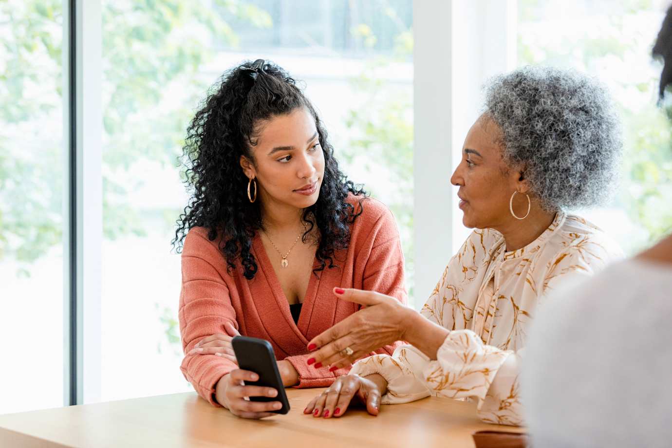 A mother and daughter look at the mom's phone for scam messages.