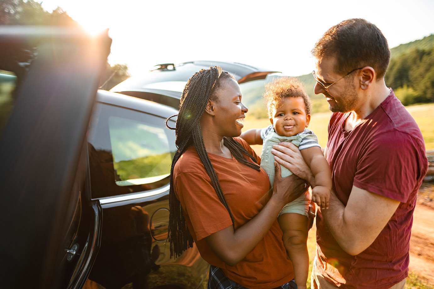interracial couple with their baby standing outside their Hertz car rental