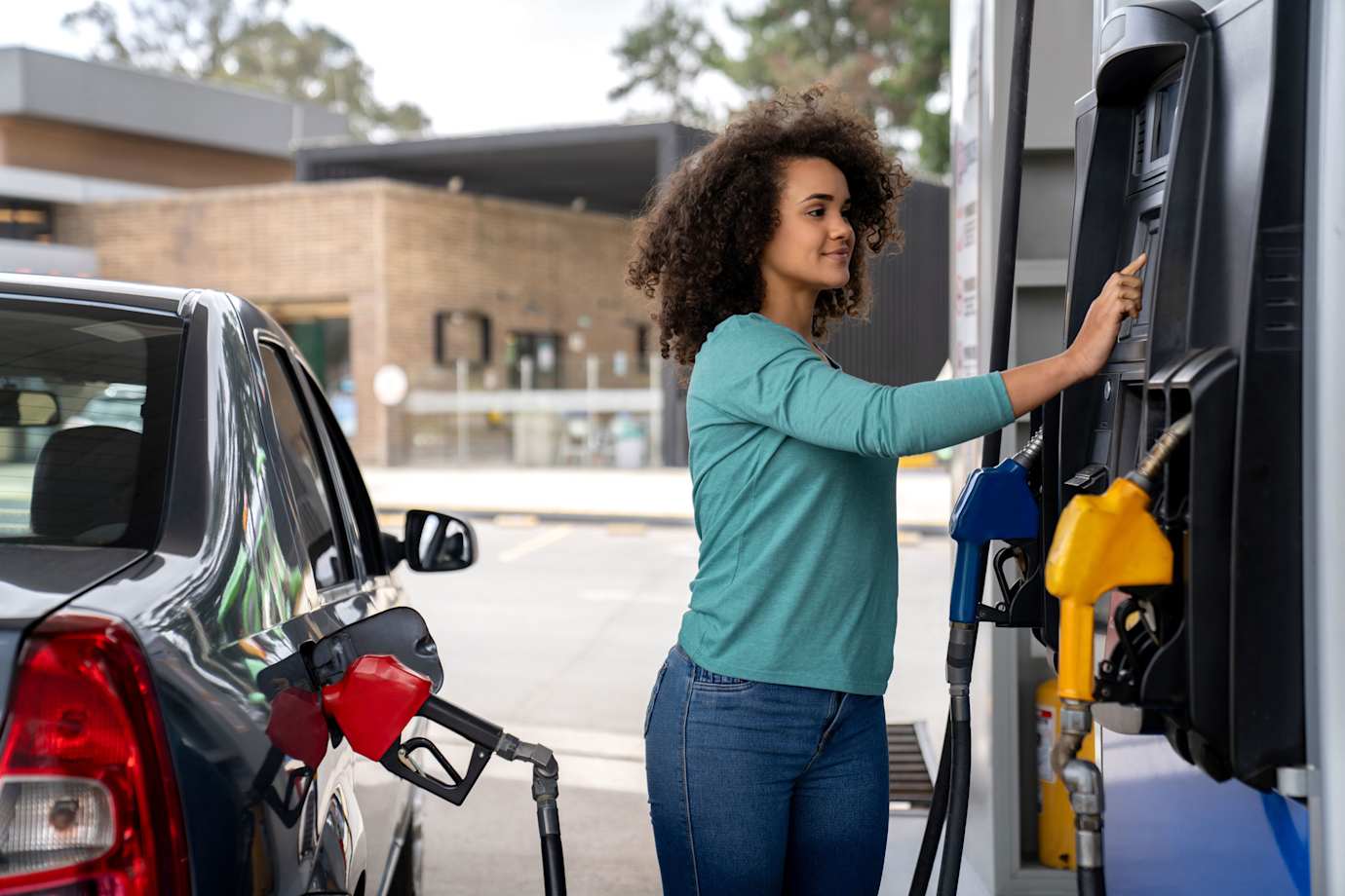 A woman selects her preferred gas at a gas station.