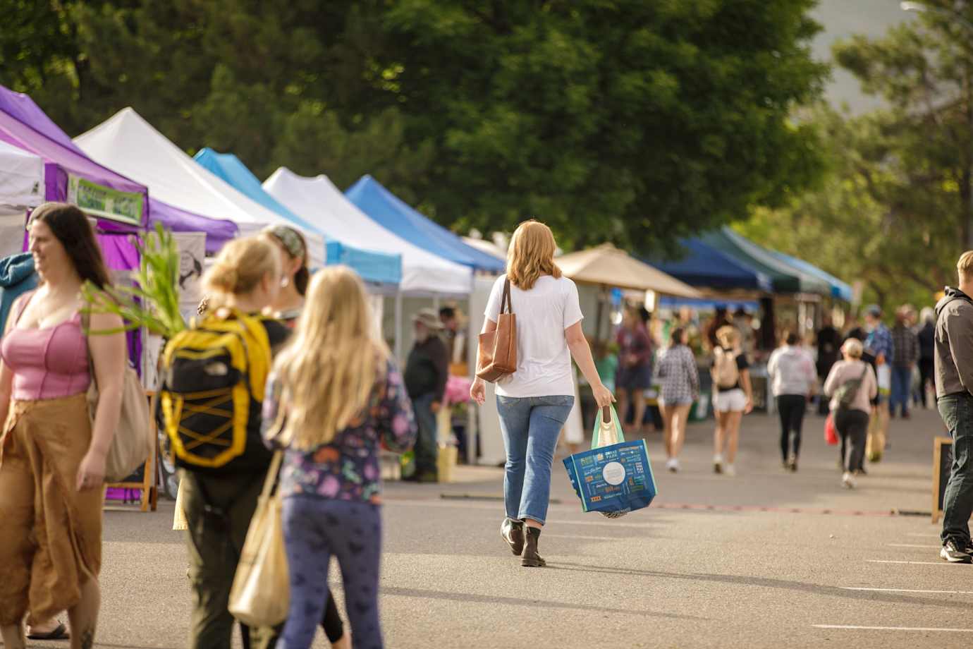 Shoppers walk between booths at the Clark Fork River Market in Missoula, Montana.