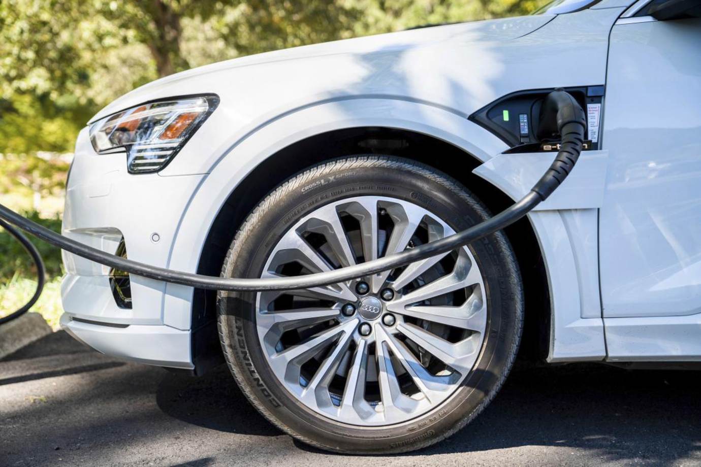An Audi E-tron plugged into an EV charger.