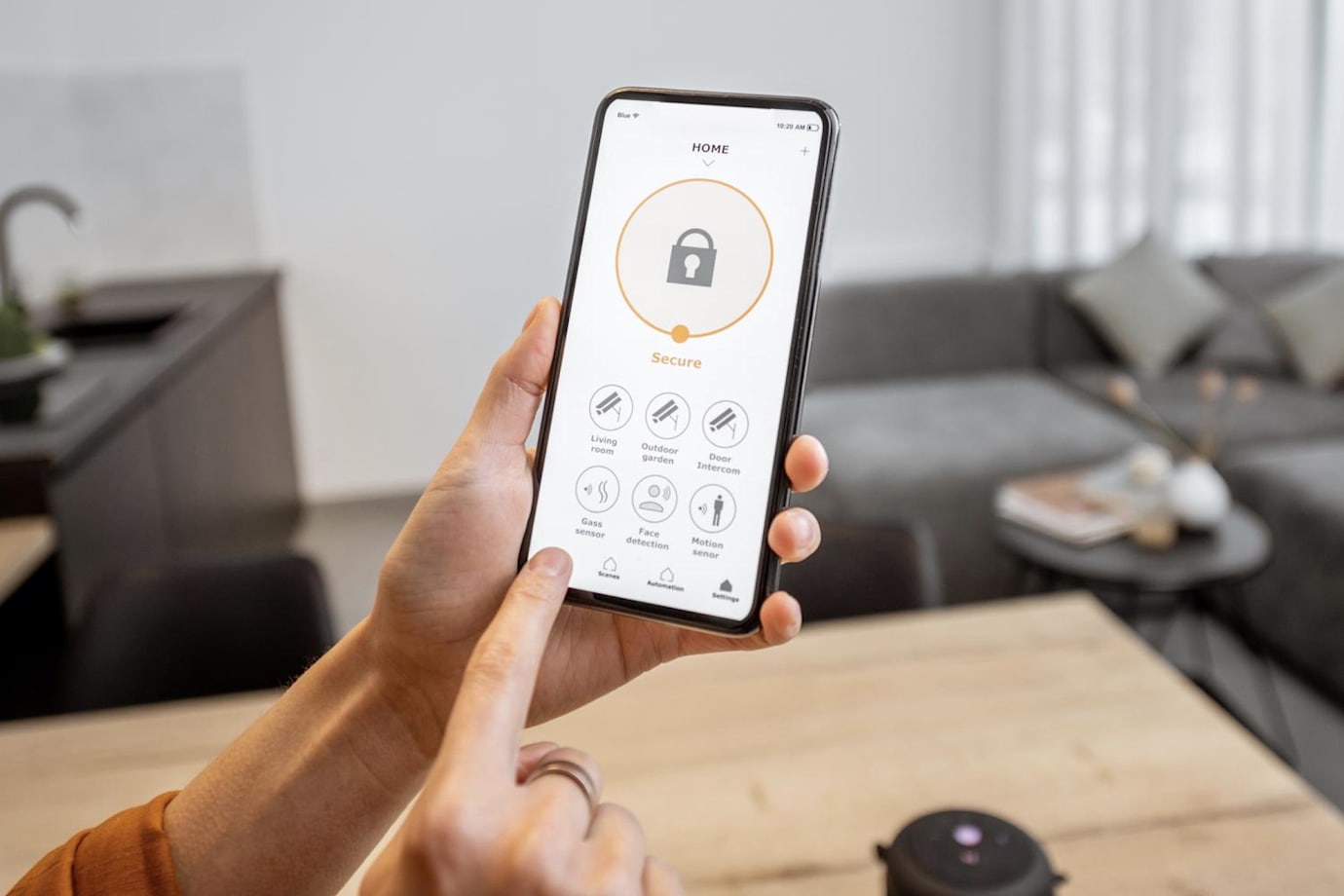 a hand holds a smartphone and uses a home security app.