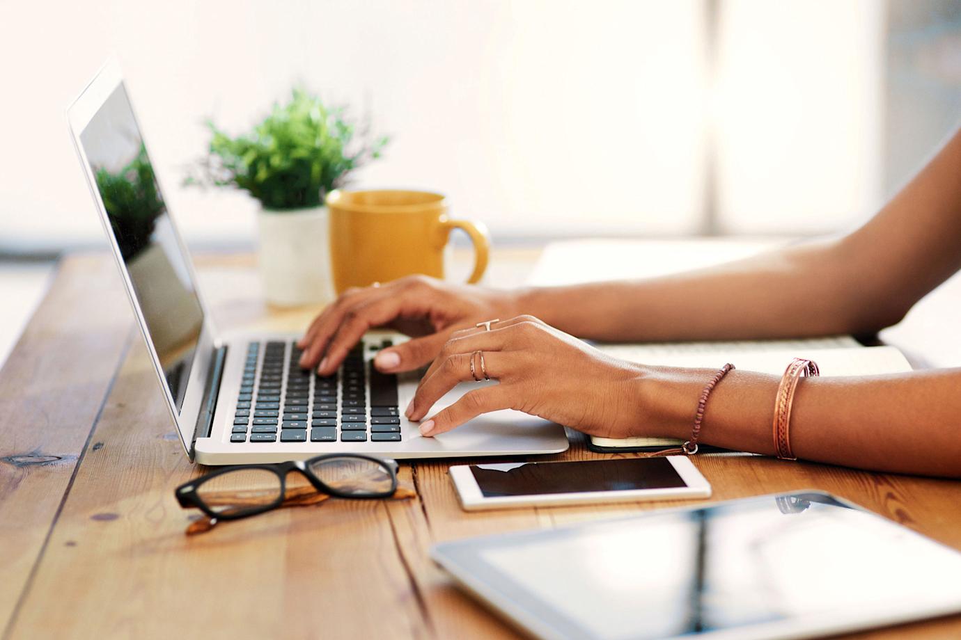 A woman uses her computer at the breakfast table.