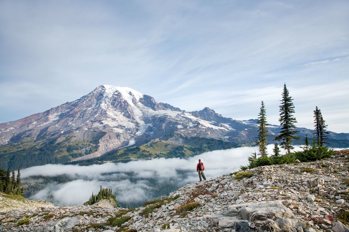 solo hiker takes in the panoramic view of Mount Rainier from Pinnacle Peak Trail in Washington