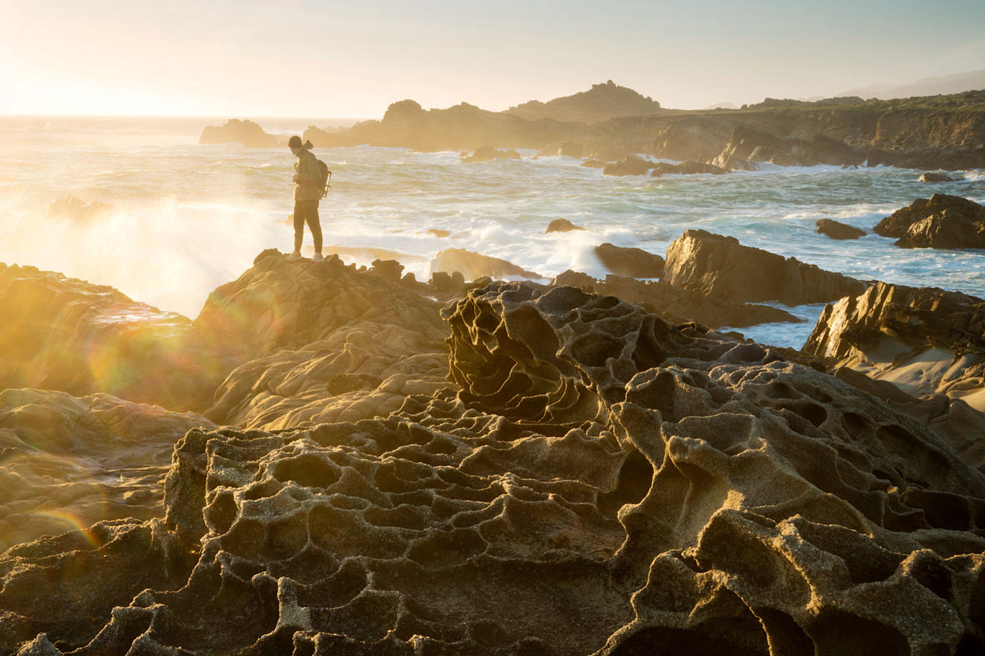 A visitor standing on the honeycombed rocks known as tafoni at Salt Point.