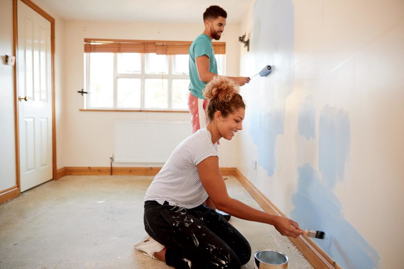 A couple paint a bedroom together.